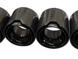 Four carbon fiber exhaust tips featuring a sleek design with perforated inner linings, displaying a logo with 
