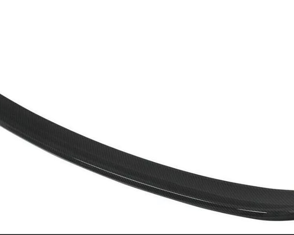 A black, curved car spoiler made of carbon fiber material is displayed against a plain white background.