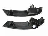 Two black car mirror indicators, each with a sleek curved shape and mounting clips, lie against a white background, showcasing their design and structure for automotive use.