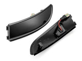 Two sleek, curved black car light covers rest side by side; one shows a red wire inside, set against a plain white background.