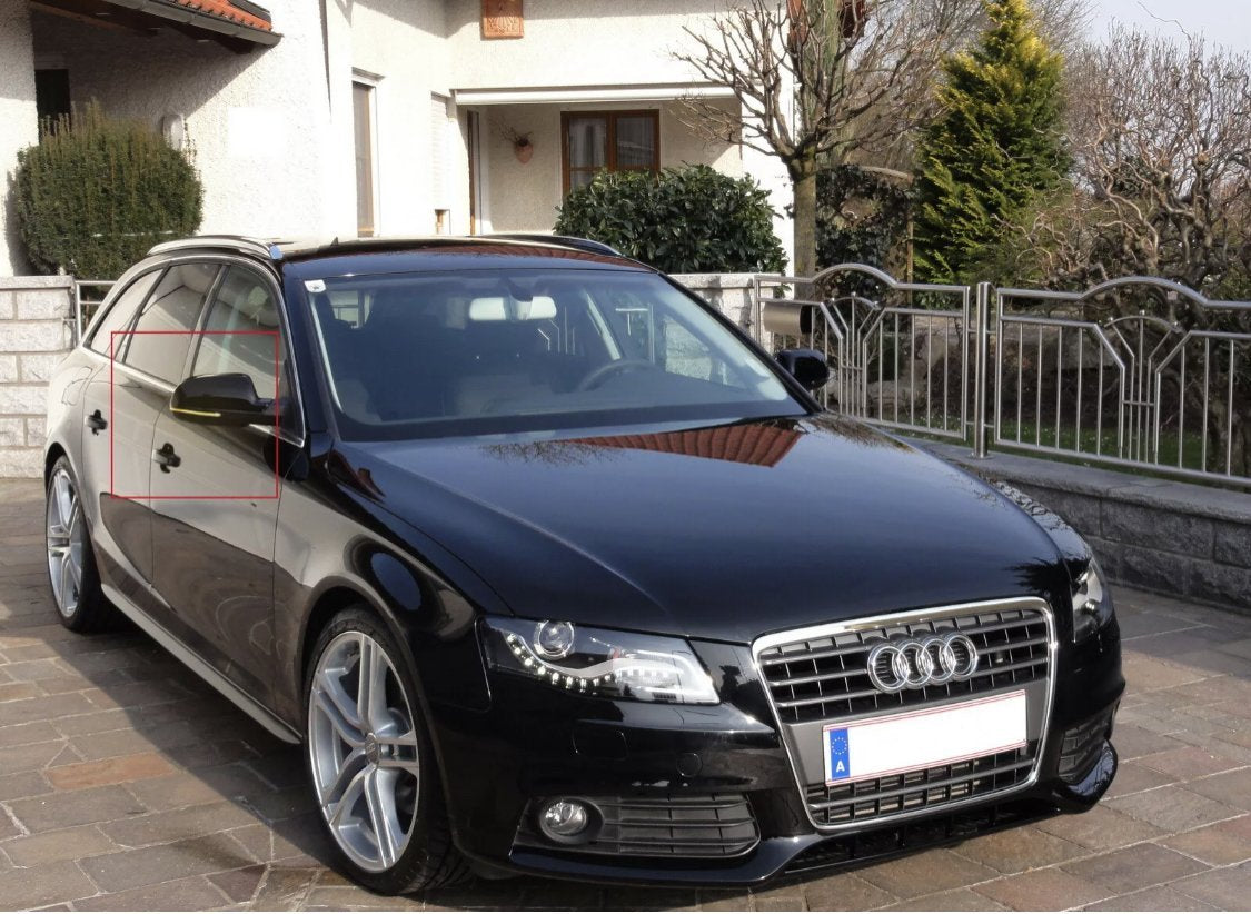 A black car is parked on a driveway outside a house, with a red rectangle marking the driver's side window and mirror. There’s a stone fence and greenery nearby.