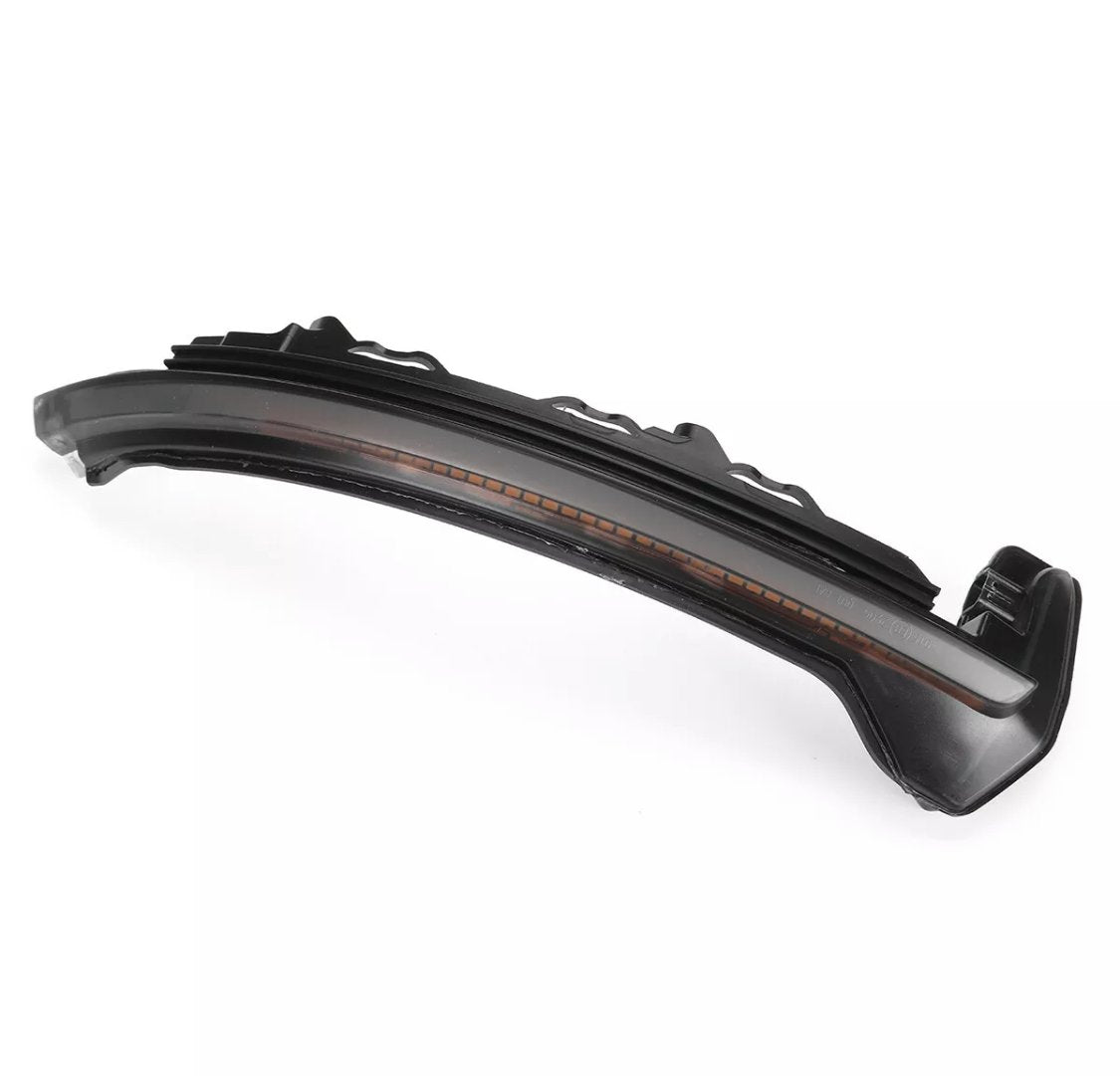 Curved black car part, likely a side mirror indicator light, with an orange strip inside. Placed on a plain white background, highlighting its sleek, aerodynamic design.