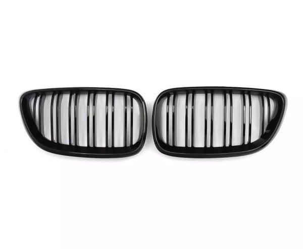 Two black kidney-shaped car grilles with vertical slats, positioned side by side against a plain white background.