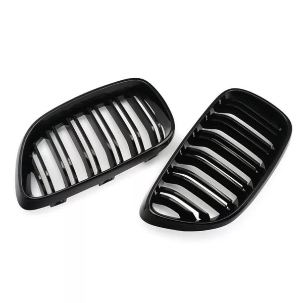 Two black, kidney-shaped car grilles with vertical slats lie on a white background, suggesting automotive parts likely used for air intake and vehicle front decoration.