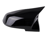 A sleek black car side mirror cover with a pointed design, resting on a white background, reflecting light slightly.