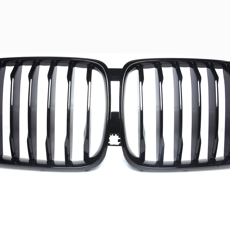 A shiny black car grille with vertical slats, forming two adjacent kidney-shaped sections, set against a plain white background.