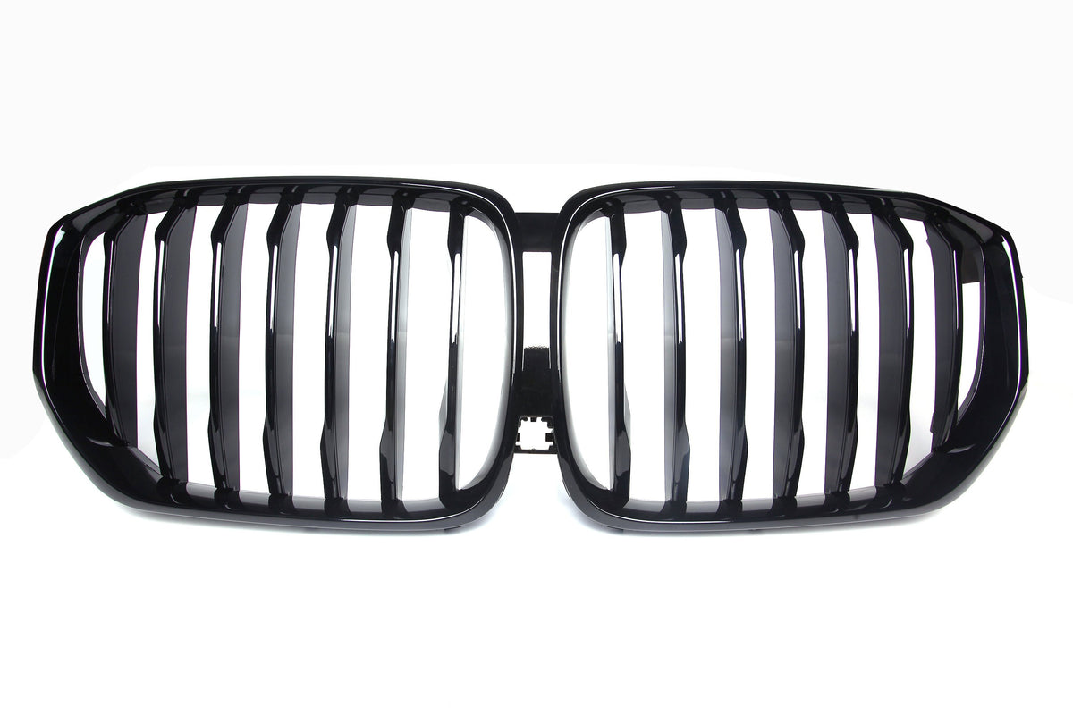 A shiny black car grille with vertical slats, forming two adjacent kidney-shaped sections, set against a plain white background.