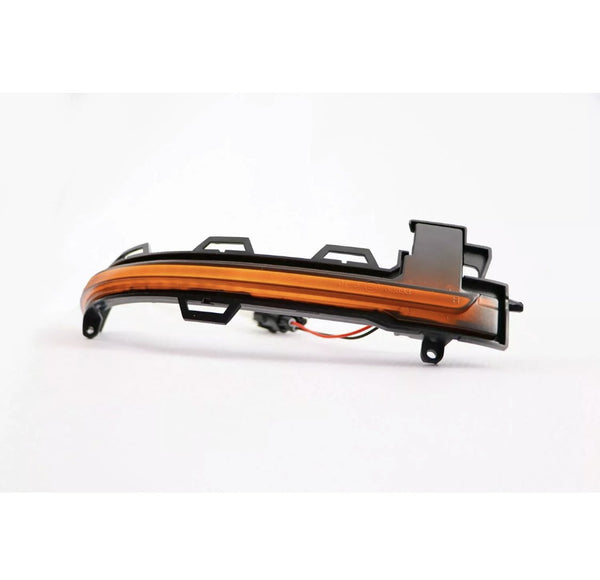 A curved, orange automotive light fixture with connectors sits on a white surface, accompanied by visible wires extending from its base.