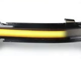 A sleek, curved car turn signal light illuminates in a bright yellow. The light is enclosed in a black and transparent casing, set against a plain white background.