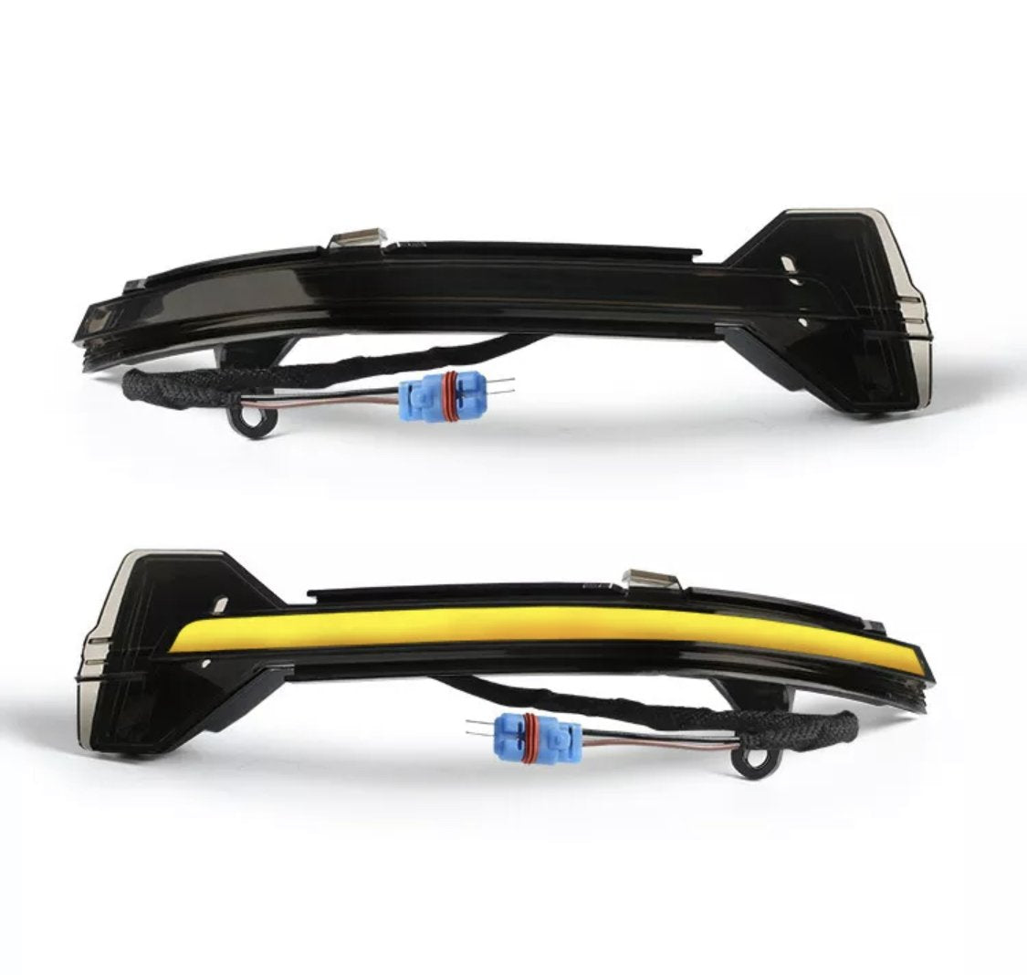 Two car side mirror indicators, one outlined with a yellow strip, display wiring connectors. They are positioned on a white background, highlighting their curved design and blue connectors.