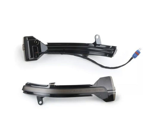Two black automotive light strips, one with a blue connector, lie on a plain white surface. They have mounting brackets and appear designed for a vehicle's exterior.