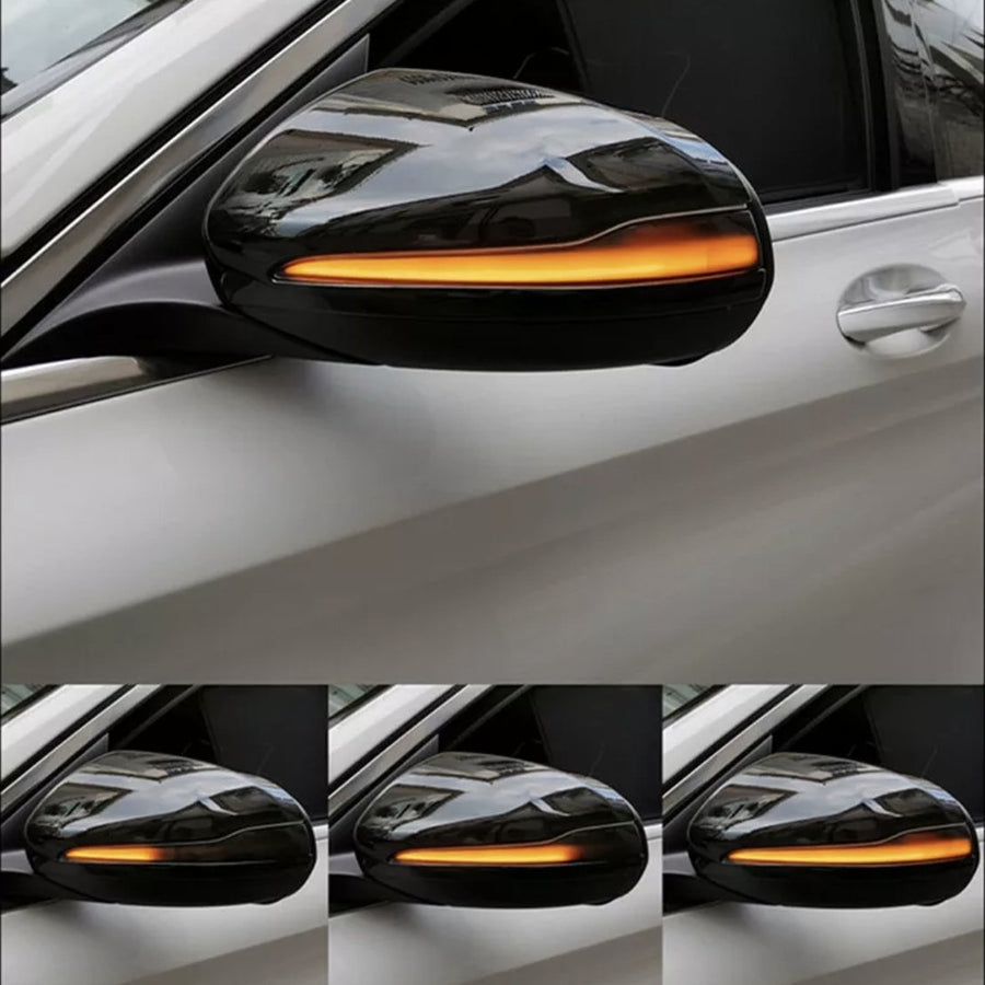 A car's side mirror with an integrated amber light blinking sequentially, mounted on a white vehicle, shown in multiple frames captured from the side.