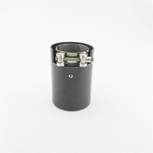 A cylindrical metallic exhaust tip with a carbon fiber exterior and clamp mechanism is placed upright on a plain white surface.