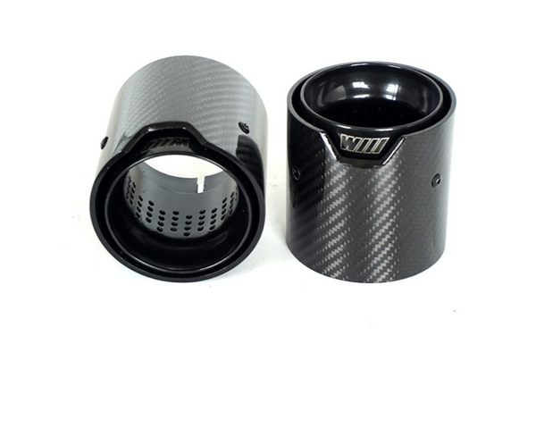 Two carbon fiber cylindrical exhaust tips are positioned upright and slightly angled against a white background. Each has a visible perforated inner surface; one displays the text "WIII" on its edge.
