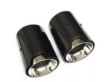 Two carbon fiber exhaust tips are displayed side by side, with a glossy black exterior and a metallic interior, on a plain white background. The text 