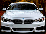 A white BMW car sits stationary on a leaf-covered ground, surrounded by autumn trees with colorful foliage.