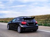 A black car is driving on an open highway, flanked by grassy fields, under a cloudy sky.
