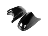 Two sleek, black plastic mirror covers rest on a white background, showcasing a glossy finish with smooth curves and aerodynamic design.