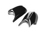 Two glossy, black side view mirror covers for a vehicle are placed on a plain white background, showcasing their sleek, aerodynamic design.