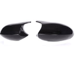 Two glossy black side mirror covers are placed against a white background, one on the left and one on the right, separated by space.