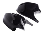 Two sleek, glossy black car mirror covers rest on a white background, reflecting light. The aerodynamic design suggests a modern vehicle accessory, with each piece symmetrical and curved.