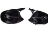 Two black plastic car mirror covers, facing upward, positioned side by side on a plain white background.