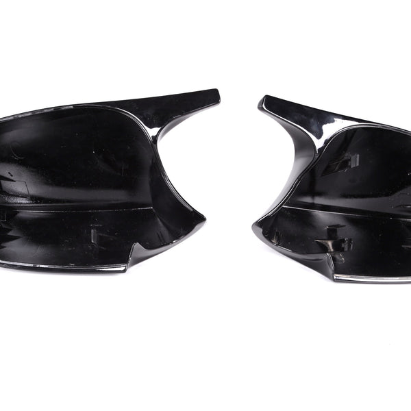 Two black plastic car mirror covers, facing upward, positioned side by side on a plain white background.