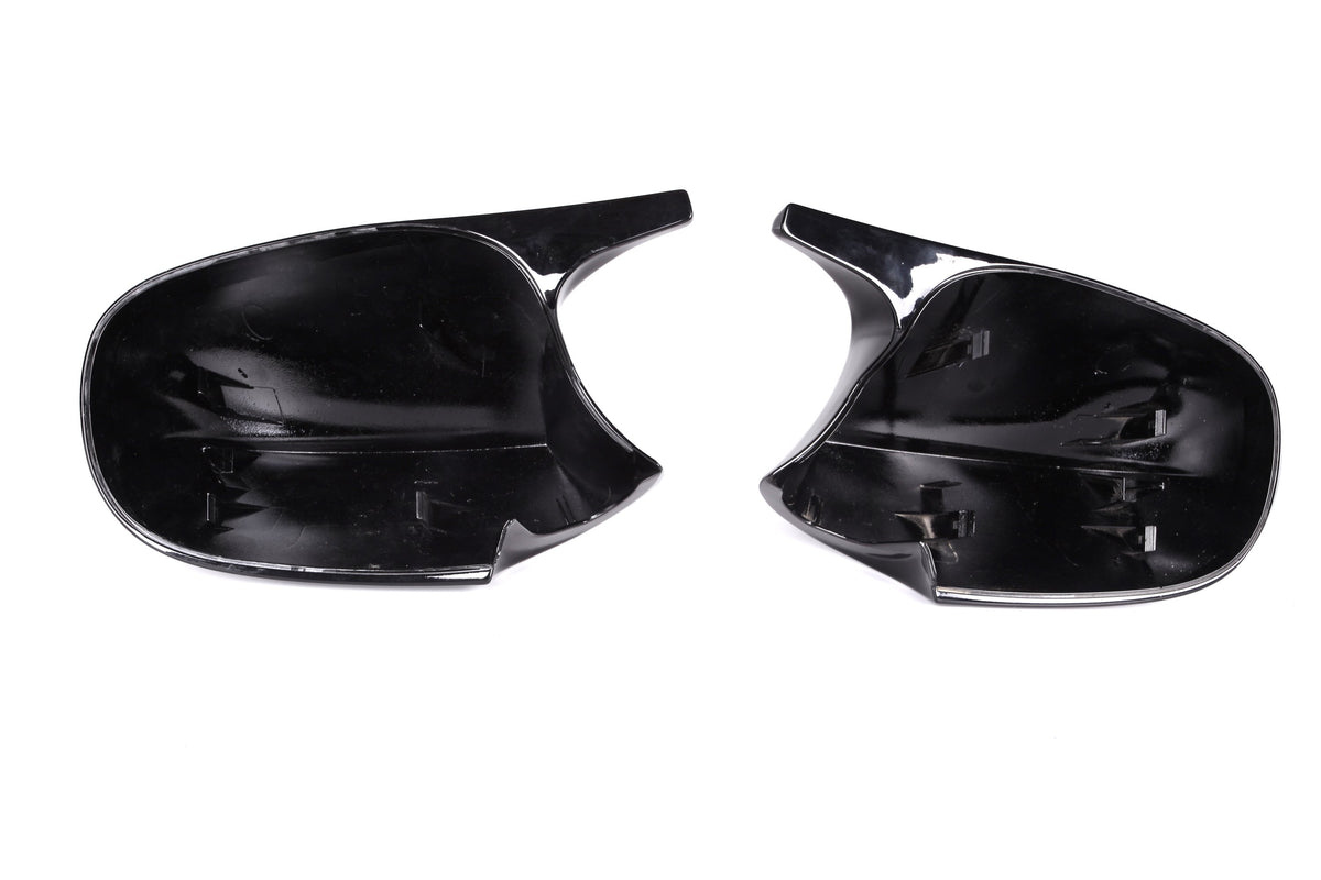 Two black plastic car mirror covers, facing upward, positioned side by side on a plain white background.