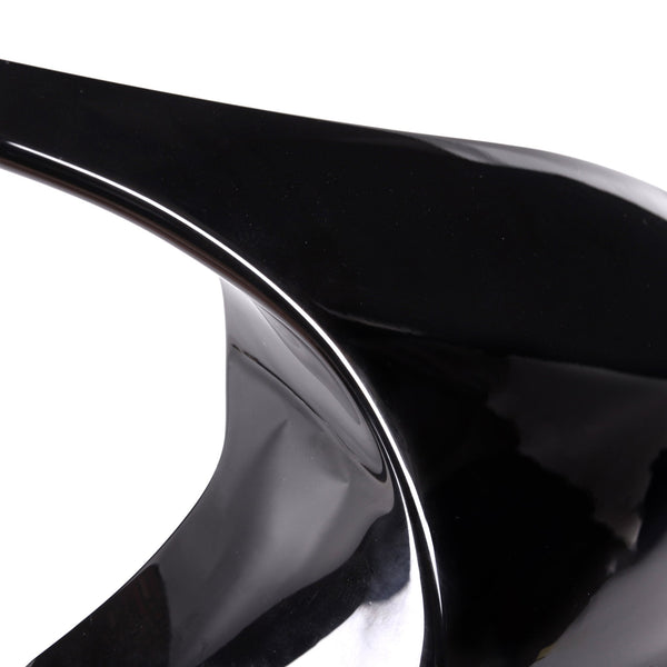 A glossy black high-heeled shoe with a dramatic curved arch stands against a plain white background, highlighting its sleek, artistic design.