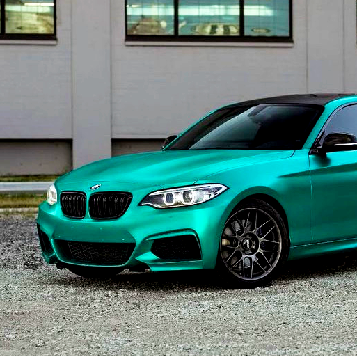 A teal sporty car is parked on a gravel surface against a backdrop of a building with several windows.