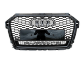A car grille features a honeycomb pattern, with the Audi logo and the word "quattro" prominently displayed on a metallic surface, set against a gray background.