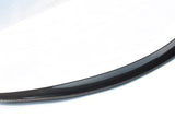 Curved carbon fiber car spoiler resting against a white background, showcasing its sleek, aerodynamic design.