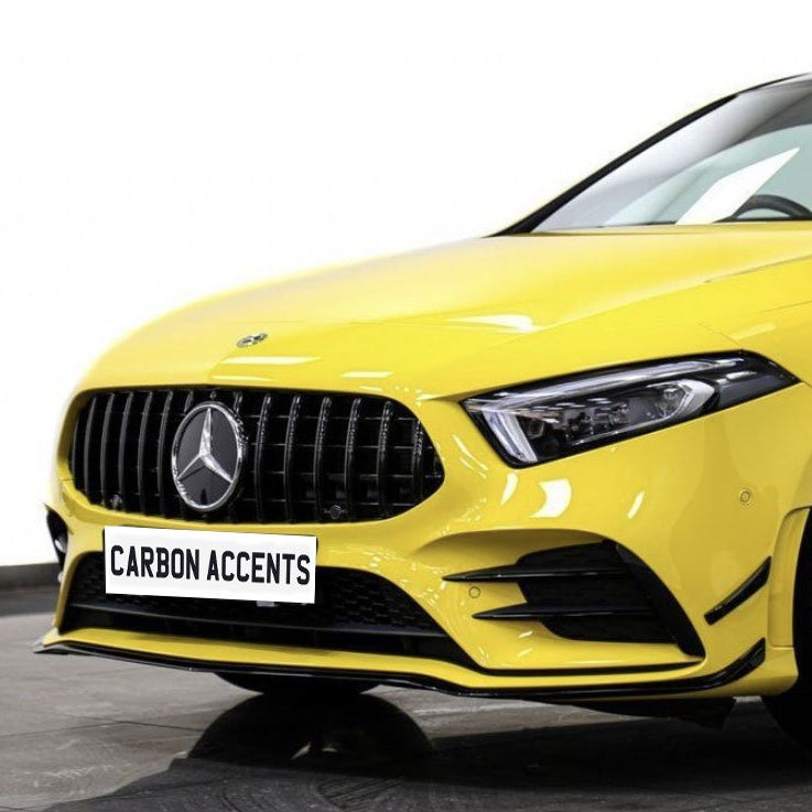 Yellow luxury car with a prominent logo is parked on a showroom floor. The license plate reads "CARBON ACCENTS." The car features sleek black wheels and a modern design.