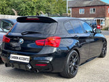 A black BMW hatchback is parked on a concrete surface, featuring tinted windows and red taillights. The car's license plate reads 